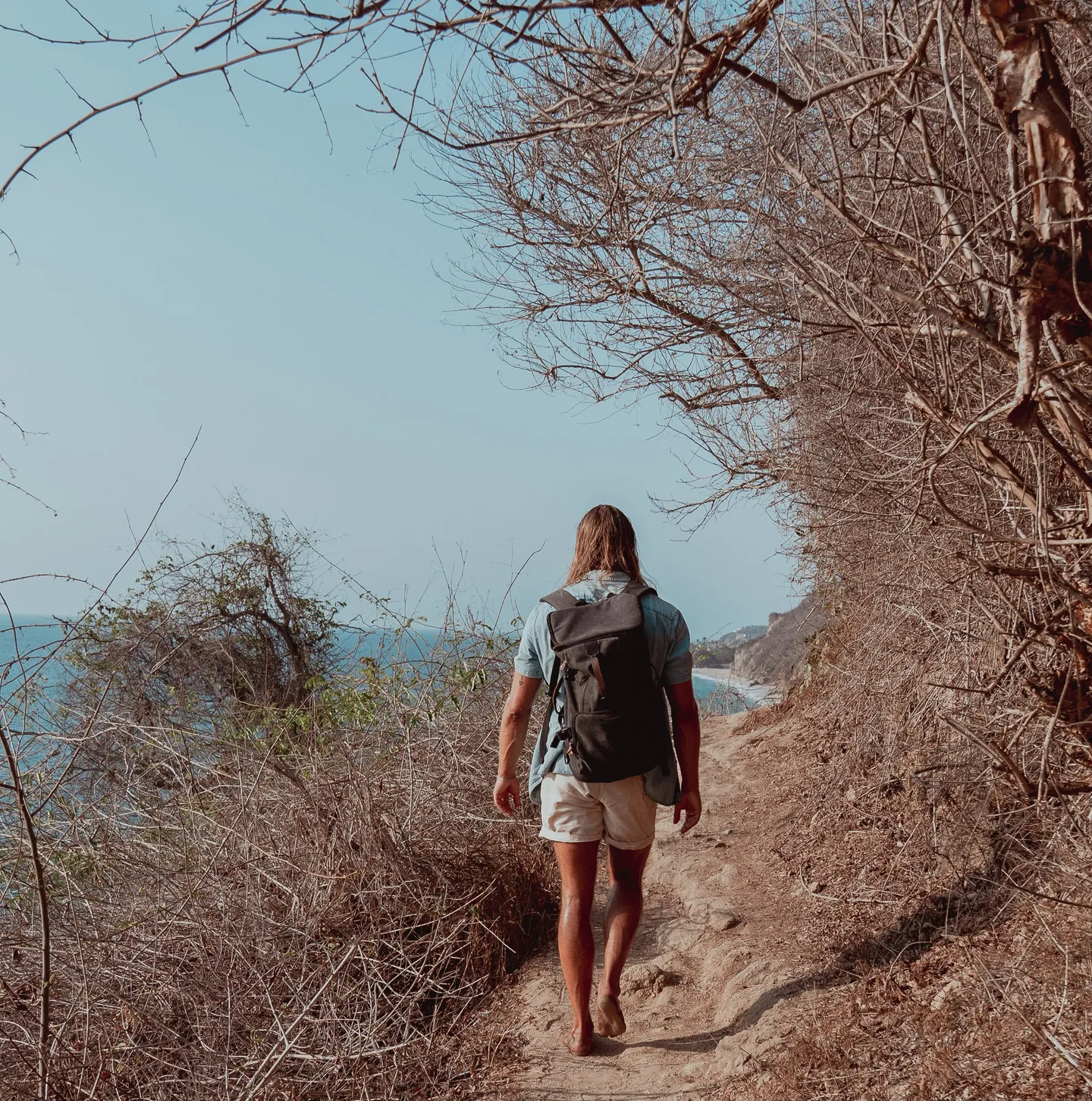 Christian hiking barefoot along a coastal trail